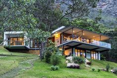 the house is surrounded by lush green grass and trees, with stairs leading up to it