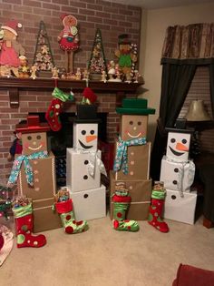 snowmen made out of boxes and stockings in front of a fireplace with christmas decorations