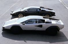 two cars are parked side by side in the parking lot, one is black and white