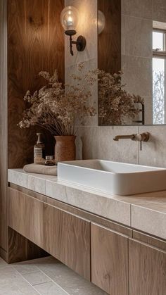 a bathroom with two sinks, mirrors and vases on the counter top in front of it