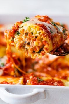 a spoon full of lasagna sauce being lifted from a casserole dish