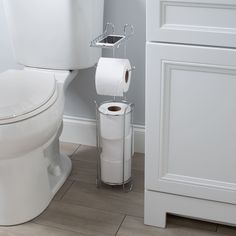 a white toilet sitting in a bathroom next to a roll of paper on the floor