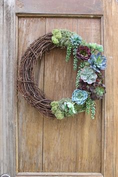 a wreath with succulents and greenery hangs on a door