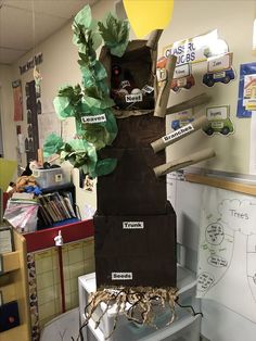 a sculpture made out of cardboard with leaves and branches on it in an office cubicle