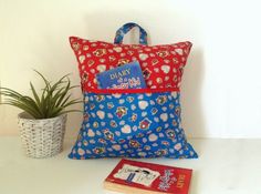 a blue and red pillow sitting on top of a white table next to a potted plant