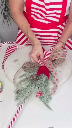 a woman is decorating a glass jar with candy canes and greenery in it