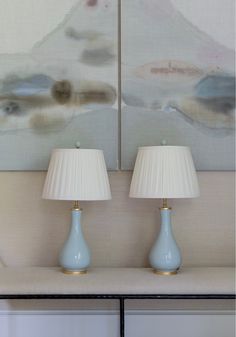 two lamps sitting on top of a table next to a painting