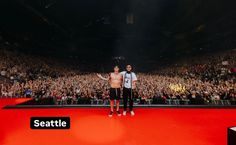 two men standing on top of a stage in front of a large group of people