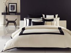 a bed with black and white comforters in a modern style bedroom, along with a side table