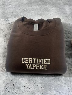 Introducing our Certified Yapper Embroidered Unisex T-Shirt or Crewneck Sweatshirt! Get ready to yap with this humorous design featuring a bold Certified Yapper logo in classic college lettering. Made from 100% cotton, the t-shirt is available in a comfortable unisex size while the crewneck sweatshirt is a cozy blend of 50% cotton and 50% polyester. Show off your certified yapper status to all your friends with this must-have apparel! This fun and stylish design is perfect for those who love to Brown Crew Neck Top With Embroidered Logo, Brown Cotton Sweatshirt With Embroidered Logo, Un Logo, Really Cute Outfits, Cute Fits, Stylish Design, Crewneck Sweatshirt, Unisex T Shirt, Sweat Shirt