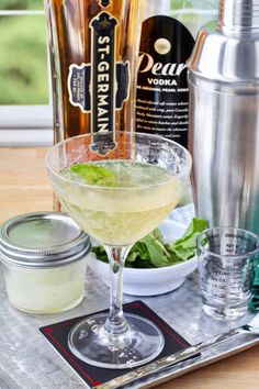 a drink in a glass sitting on top of a metal tray next to bottles and glasses