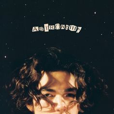 a young man with curly hair is looking at the camera and has words above his head