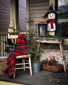 a porch decorated for christmas with an old chair and snowman