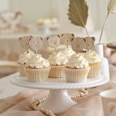 cupcakes on a cake plate with wooden bear toppers in the shape of hearts