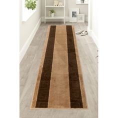 a brown and beige rug on the floor in front of a white book shelf filled with books