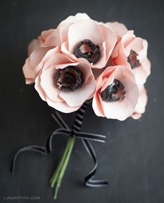 some pink flowers are sitting on a black table and it looks like they have been made out of paper