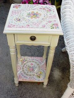 a white table with flowers painted on it and a wicker chair next to it