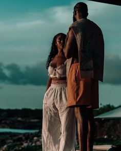 a man standing next to a woman near the ocean