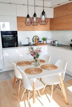 a white table with four chairs and a vase filled with flowers on top of it