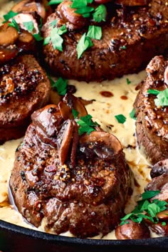 some very tasty looking steaks with sauce and parsley on top in a skillet