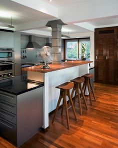 a modern kitchen with wood floors and stainless steel appliances