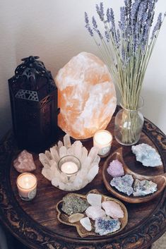 a table topped with crystals and candles next to a vase filled with lavenders on top of a wooden table