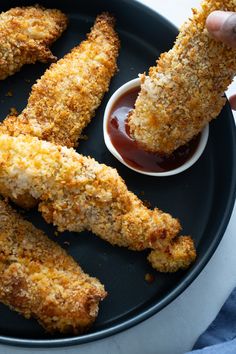 fried chicken sticks with ketchup and dipping sauce on a black plate, ready to be eaten