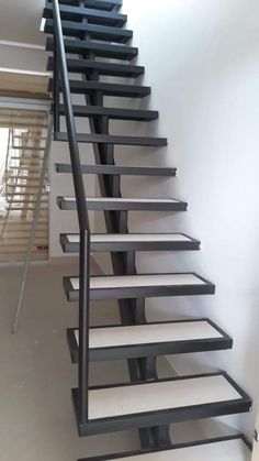 a black and white stair case in a room with no carpet on the floor, next to a window