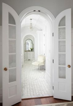 an open door leading into a bathroom with white walls and flooring on the other side