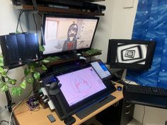 a computer desk with two monitors and a laptop on it, in front of a blue wall