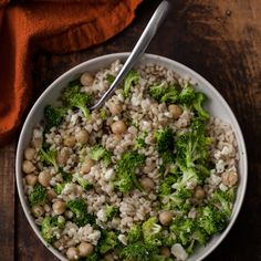 a bowl filled with rice, broccoli and beans on top of a wooden table