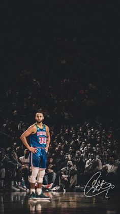 a man standing on top of a basketball court with his hands on his hips while wearing a blue uniform