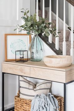 a vase filled with flowers sitting on top of a wooden table next to a stair case