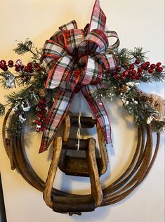 a wooden sled hanging on the wall next to a christmas wreath with red berries and greenery