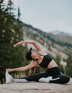 a woman doing yoga on top of a mountain