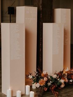 candles and flowers are sitting on the floor next to two tall white boxes with names