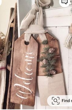 a wooden sign hanging from the side of a door with pine cones and burlocks