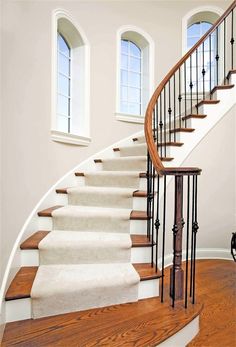 a white staircase with wooden handrails next to two windows