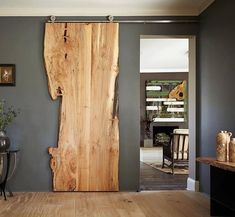 a wooden door is open in a room with gray walls and wood flooring, along with pictures on the wall