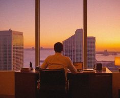 a man sitting at a desk in front of a window