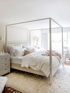 a bedroom with a four poster bed and white furniture