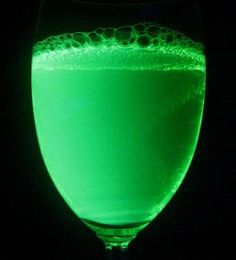 a green liquid in a wine glass on a black background