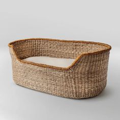 an empty wicker dog bed with a white pillow in the bottom and tan lining