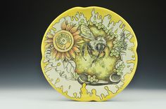 a yellow plate with a bee and sunflowers painted on the front, sitting on a table