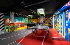 an indoor ping pong table in the middle of a room with colorful painted walls