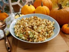 a bowl filled with macaroni and cheese next to pumpkins on a table