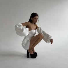 a woman in a white dress is posing for the camera