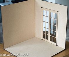 an open cardboard box with a window on the front and side, sitting on top of a wooden table