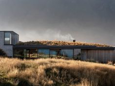 the house is surrounded by tall grass and has a roof that looks like it's on top of a hill