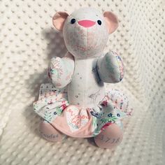 a small stuffed animal sitting on top of a white blanket with pink and blue flowers